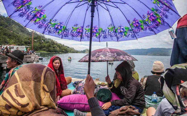 Family members sit together as they wait for rescue teams searching for missing passengers at the Lake Toba ferry port in the province of North Sumatra on June 20, 2018, after a boat capsized on June 18. Nearly 180 passengers are missing after the ferry sank into the depths of a volcanic lake in Indonesia, police said on June 20, almost tripling initial estimates – but the search- and- rescue agency cautioned it was still unclear how many people were aboard the vessel when it capsized. (Photo by Ivan Damanik/AFP Photo)