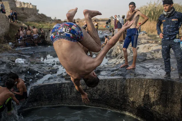 Men bath and swim at thermal springs after returning to their homes on November 9, 2016 in Hammamal-Alil, Iraq. Many families have begun returning to their homes in recently liberated towns south of Mosul. Oil wells in the area that were set on fire by ISIS continue to burn blanketing the area in think clouds of smoke and oil. (Photo by Chris McGrath/Getty Images)