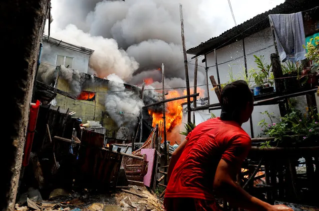 A resident throws water at his house on fire at a residential neighbourhood of an informal settlement, in Muntinlupa, Metro Manila, Philippines on June 21, 2018. (Photo by Erik De Castro/Reuters)