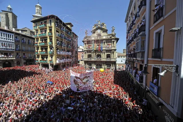 Participants hold red scarves as they celebrate the “Chupinazo” to mark the start at noon sharp of the San Fermin Festival on July 6, 2013 in front of the Town Hall of Pamplona, northern Spain. Tens of thousands of people packed Pamplona's streets for a drunken kick-off to Spain's best-known fiesta: the nine-day San Fermin bull-running festival. (Photo by Rafa Rivas/AP Photo)