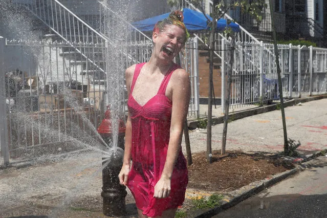 A woman cools off from the extreme heat from an opened fire hydrant in Brooklyn, New York on July 2, 2018. (Photo by Shannon Stapleton/Reuters)