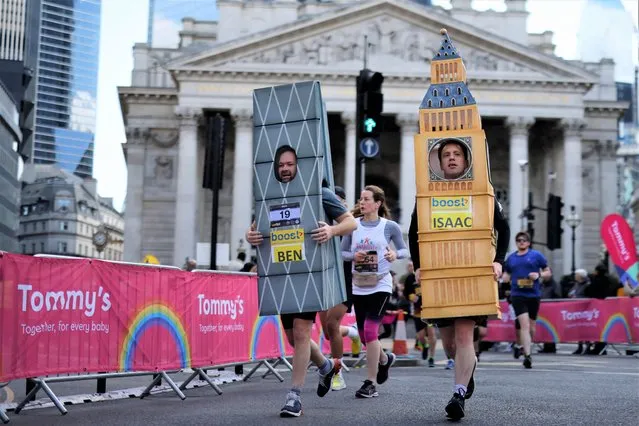 A runner dressed-up as Elizabeth Tower, commonly known by the name of the clock's bell, Big Ben (R) passes by the Bank of England as he competes in the 2022 London Landmarks Half Marathon, in London, on April 3, 2022. (Photo by Tolga Akmen/AFP Photo)