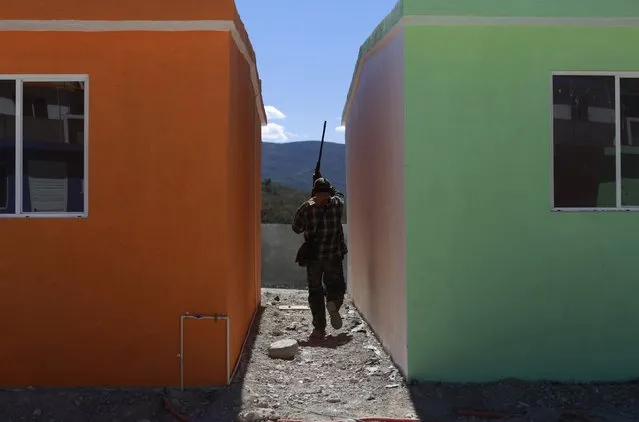 A member of the Community Police of the FUSDEG (United Front for the Security and Development of the State of Guerrero) searches for a man, who ran away upon seeing the Community Police approach as they patrolled a street, in the village of Petaquillas, on the outskirts of Chilpancingo, in the Mexican state of Guerrero, February 1, 2015. (Photo by Jorge Dan Lopez/Reuters)