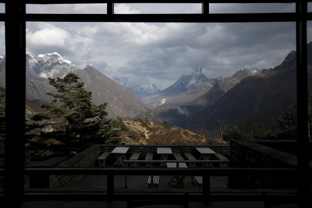 A view, through a window, of Mount Ama Dablam (R) is seen as Mount Everest (C) is covered with clouds, at an empty Everest view hotel in Solukhumbu district, also known as the Everest region, in this picture taken November 30, 2015. (Photo by Navesh Chitrakar/Reuters)