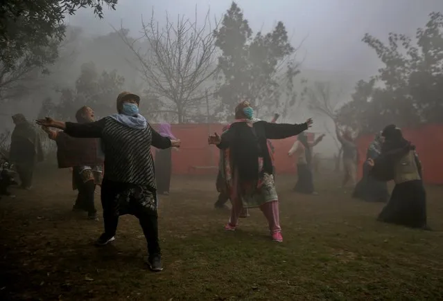 Woman attend their yoga exercise in a park while heavy fog enveloping the areas of Lahore, Pakistan, Wednesday, February 17, 2021. (Photo by K.M. Chaudary/AP Photo)