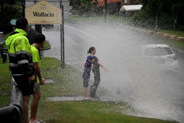 Children react as they are sprayed with floodwaters while motorists commute on a road near Warragamba Dam in Sydney on March 21, 2021, as Sydney braced for its worst flooding in decades after record rainfall caused its largest dam to overflow and as deluges prompted mandatory mass evacuation orders along Australia's east coast. (Photo by Saeed Khan/AFP Photo)