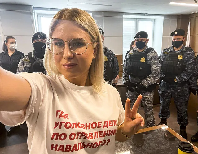 In this handout photo released by Russian opposition activist Lyubov Sobol in her twitter.com/SobolLubov account, Russian opposition activist Lyubov Sobol wearing in t-short with the words reading “where is the criminal case for the poisoning of Navalny?” makes a selfie in front of Russian Federal Bailiffs service officers in a courtroom in Moscow, Russia, on Thursday, April 15, 2021. Sobol, a top associate of Russia's imprisoned opposition leader Alexei Navalny was convicted of trespassing Thursday and handed a suspended sentence of one year community service after she tried to doorstep an alleged security operative believed to be involved in Navalny's poisoning with a Soviet-era nerve agent. (Photo by twitter.com/SobolLubov via AP Photo)