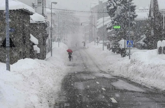 People walk down the road during a snowstorm in Villablino, northern Spain, February 5, 2015. (Photo by Eloy Alonso/Reuters)