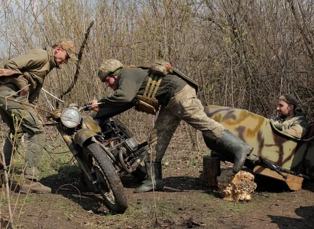 Service members of the Ukrainian armed forces fix a motorcycle at fighting positions on the line of separation near the rebel-controlled city of Donetsk, Ukraine April 21, 2021. (Photo by Serhiy Takhmazov/Reuters)