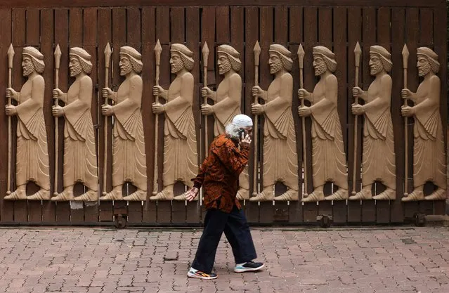 A devotee walks past a gate of a Parsi fire temple featuring carvings of ancient priests on the occasion of the Parsi New Year in Mumbai, India on August 16, 2023. (Photo by Francis Mascarenhas/Reuters)