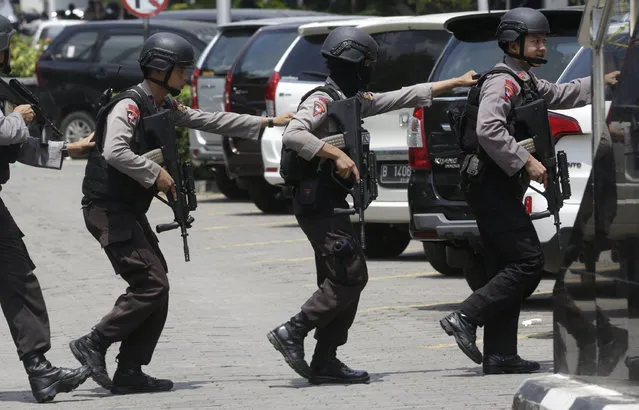 Police officers take their position near the site where an explosion went off in Jakarta, Indonesia Thursday, January 14, 2016. Suicide bombers exploded themselves in downtown Jakarta on Thursday while gunmen attacked a police post nearby, a witness told The Associated Press. Local television reported more explosions in other parts of the city. (Photo by Dita Alangkara/AP Photo)