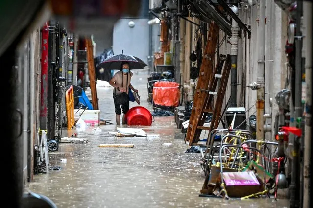 A woman walks in a flooded back alley in Hong Kong on September 8, 2023. Record rainfall in Hong Kong caused widespread flooding in the early hours on September 8, disrupting road and rail traffic just days after the city dodged major damage from a super typhoon. (Photo by Mladen Antonov/AFP Photo)