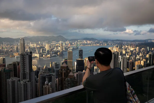 A man takes photos of Victoria Harbour from a panoramic terrace in Hong Kong, China, 10 May 2021. Hong Kong resumed local tours ​under a new “vaccine bubble” after six-month hiatus. (Photo by Jerome Favre/EPA/EFE)