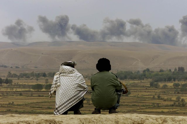 Two Northern Alliance soldiers watch as dust and smoke rise after explosions hit Taliban positions on Kalakata hill, near the village of Ai-Khanum in northern Afghanistan, November 2001. (Photo by Vasily Fedosenko/Reuters)