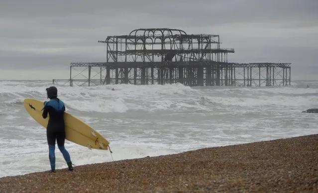 A surfer looks out at the waves on Brighton beach as Storm Angus passes southern Britain, November 20, 2016. (Photo by Hannah McKay/Reuters)
