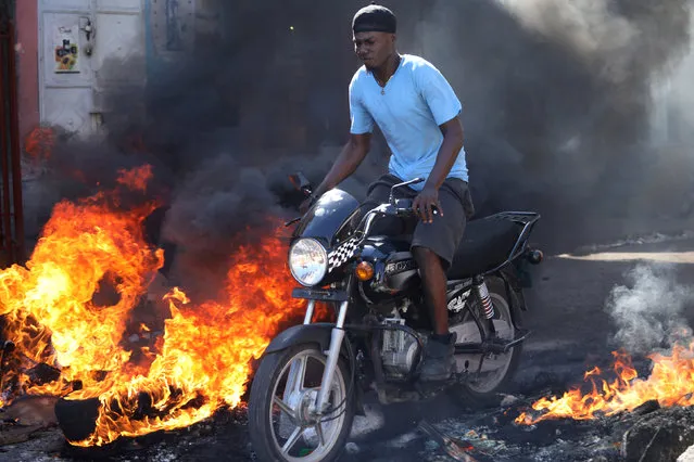 A man riding a motorbike passes over a burning barricade during a general strike in Port-au-Prince, Haiti, November 19, 2018. (Photo by Andres Martinez Casares/Reuters)