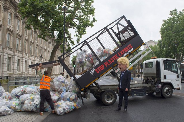 In this photo Greenpeace activists dump bags of plastic waste at the main entrance to Downing Street in a protest against the UK governments exporting of plastic waste on July 13, 2021 in London, England. 625 kilograms of plastic recycling has been dumped at Downing Street, the same volume that the UK exports every 30 seconds, and left by Greenpeace. A figure of the Prime Minister, Boris Johnson, in a Spitting Image-style mask was also at the scene. The intervention by Greenpeace comes as the Turkish government announced a U-turn on its decision to restrict imports of most types of plastic, raising the prospect of more UK recycling ending up illegally dumped or burned in Turkey. (Photo by David Mirzoeff/PA Wire Press Association)