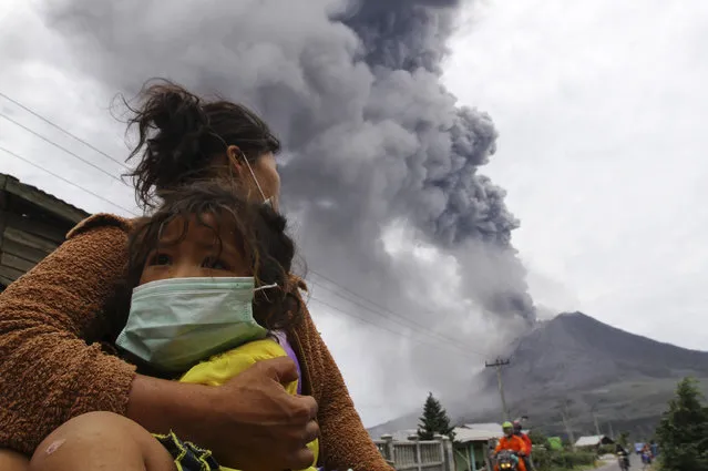 A mother holds her child as Mount Sinabung spews ash and hot lava during an eruption in Perteguhan village in Karo district, September 17, 2013. (Photo by Roni Bintang/Reuters)