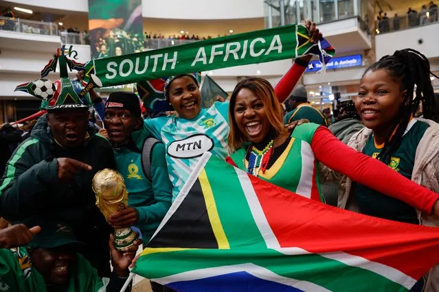 Supporters holding a South African Flag and a trophy react ahead of the South African rugby team's arrival at the OR Tambo International airport in Ekurhuleni on October 31, 2023, after they won the France 2023 Rugby World Cup final match against New Zealand. (Photo by Phill Magakoe/AFP Photo)