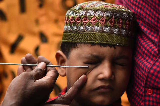A boy has his eyes smeared with traditional Kohl eyeliner before attending prayers at a Mosque on the occasion of the Eid Al-Adha festival in Chennai, India, 21 July 2021. (Photo by Idrees Mohammed/EPA/EFE)