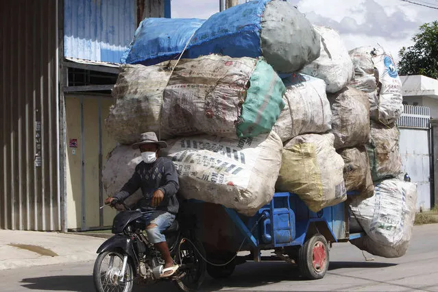 A man transports sacks loaded with scrap materials outside Phnom Penh, Cambodia, Wednesday August 11, 2021. (Photo by Heng Sinith/AP Photo)
