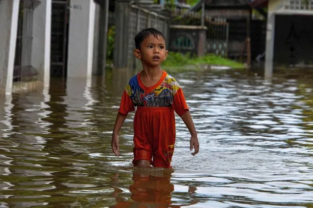 A child wades through flood water after heavy rain in the residential area of Ajun on the outskirts of Banda Aceh on July 9, 2021. (Photo by Chaideer Mahyuddin/AFP Photo)