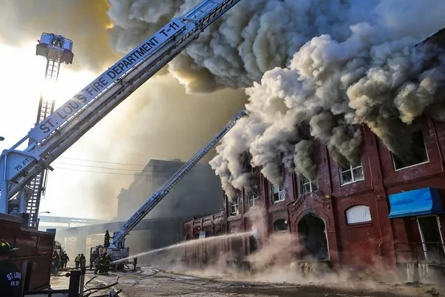 Firefighters battle a fire in the warehouse district near the St. Louis riverfront, on December 16, 2013. After breaking down the doors of the warehouse, firefighters had to retreat because of the intense heat and flame coming from the building. Over 80 firefighters were called to the scene. No one was injured. (Photo by J. B. Forbes/The St. Louis Post-Dispatch)
