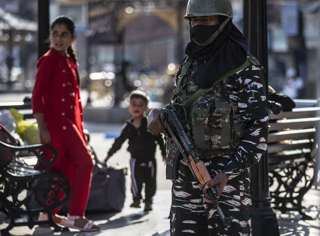Kashmiri children play as an Indian paramilitary soldier keeps guard in Srinagar, Indian controlled Kashmir, Tuesday, August 24, 2021. Indian government forces killed two senior rebel commanders and three other militants in two separate counterinsurgency operations in disputed Kashmir, police said Tuesday. (Photo by Mukhtar Khan/AP Photo)