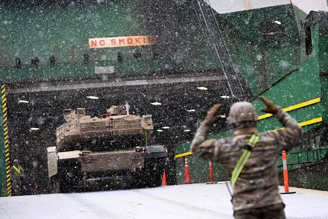 A US Army soldier signals the way to a M1A2 Abrams battle tank that will be used for military exercises by the 2nd Armored Brigade Combat Team, at the Baltic Container Terminal in Gdynia on December 3, 2022. The military equipment arrived in Poland as part of the Operation Atlantic Resolve, augmenting the air, ground and naval presence along the Eastern flank of the NATO. (Photo by Mateusz Slodkowski/AFP Photo)