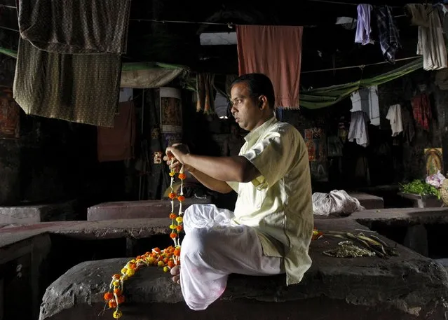 A Hindu priest makes garlands to use them in worshipping, near a flower market in Kolkata April 20, 2015. (Photo by Rupak De Chowdhuri/Reuters)