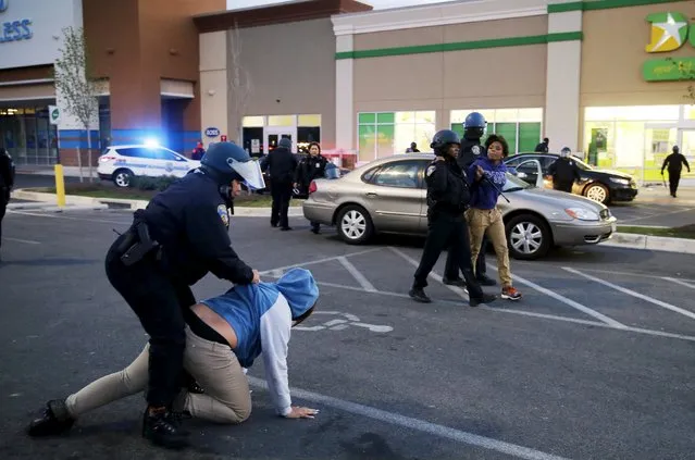 Baltimore police officers tackle and arrest looters after they emerged from a “Deals” store with merchandise during clashes between rioters and police in Baltimore, Maryland April 27, 2015. (Photo by Jim Bourg/Reuters)