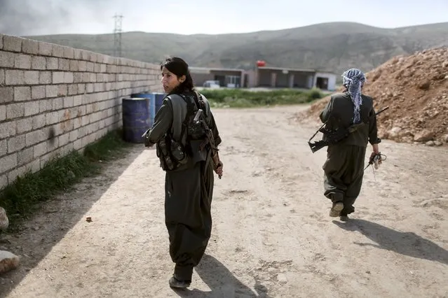Female Kurdistan Workers Party (PKK) fighters leave to join others at a position which had been hit by Islamic State car bombs in Sinjar, March 11, 2015. Women fighters at a Kurdistan Workers Party (PKK) base on Mount Sinjar in northwest Iraq, just like their male counterparts, have to be ready for action at any time. Smoke from the front line, marking their battle against Islamic State, which launched an assault on northern Iraq last summer, is visible from the base. (Photo by Asmaa Waguih /Reuters)