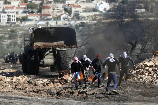 A Palestinian protester hurls a bottle containing liquid paint towards an Israeli vehicle as others run during clashes with Israeli troops following a protest against the near-by Jewish settlement of Qadomem, in the West Bank village of Kofr Qadom near Nablus February 3, 2017. (Photo by Mohamad Torokman/Reuters)