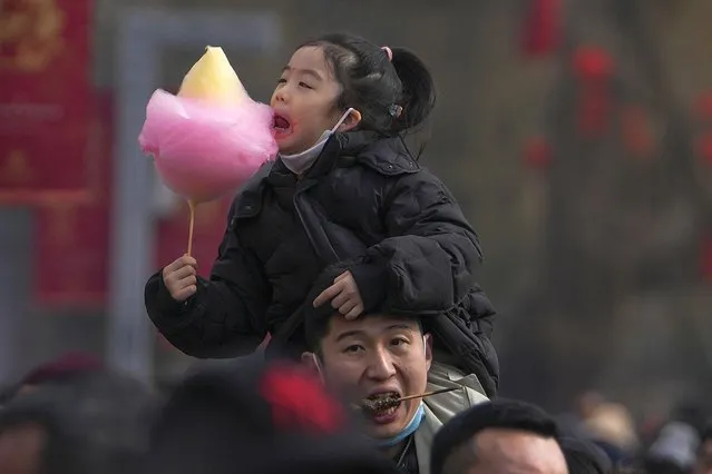A man carries his child on his shoulder as they visit the Longtan Park's temple fair during the second day of Lunar New Year celebrations in Beijing, Sunday, February 11, 2024. (Photo by Andy Wong/AP Photo)