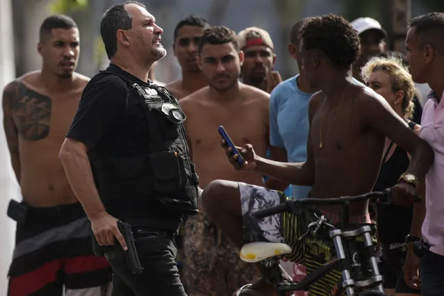 A Civil Police officer yells “get back” to a crowd calling him out for shooting a minor in the leg who was attempting to loot an electronic store, in Vitoria, Espirito Santo state, Brazil, Monday, February 6, 2017. Protests by the friends and family of military police in Espirito Santo have led to an increase in crime and forced the shut-down of some state services, authorities said Monday. The protests calling for higher pay began this weekend outside barracks throughout the small, coastal state and have prevented vehicles from leaving. (Photo by Diego Herculano/AP Photo)