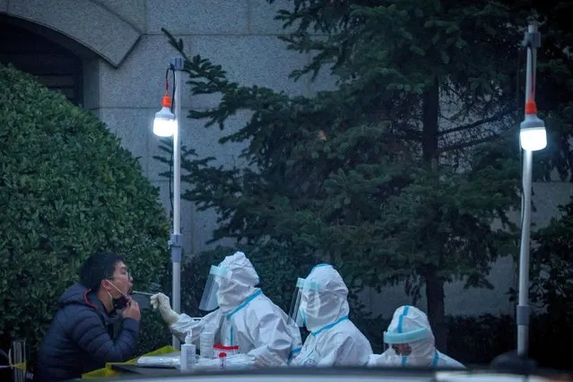 Medical personnel test a man at a makeshift testing site near a residential compound that was locked down after a local outbreak of the coronavirus disease (COVID-19) in Beijing, China, November 11, 2021. (Photo by Thomas Peter/Reuters)