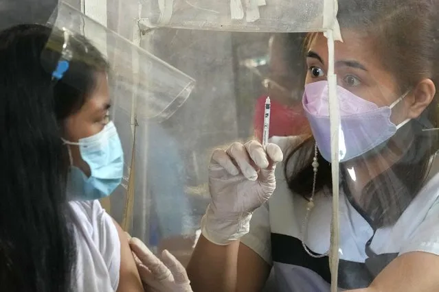 A health worker shows an empty syringe after inoculating a woman with AstraZeneca's COVID-19 vaccine during the first day of a nationwide three-day vaccination drive at a school in Quezon city, Philippines on Monday, November 29, 2021. There has been no reported infection so far caused by the new variant in the Philippines, a Southeast Asian pandemic hotspot where COVID-19 cases have considerably dropped to below 1,000 each day in recent days, but the emergence of the Omicron variant has set off a new alarm. (Photo by Aaron Favila/AP Photo)