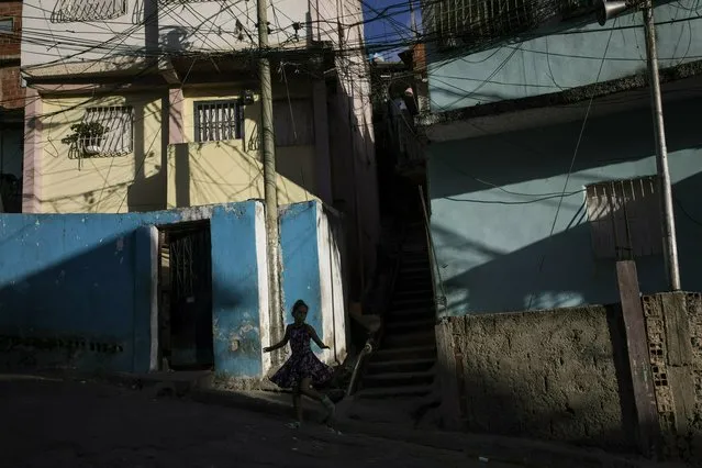 A girl runs through a neighborhood in the Petare shanty town, in Caracas, Venezuela, late Friday afternoon, May 3, 2019. (Photo by Rodrigo Abd/AP Photo)