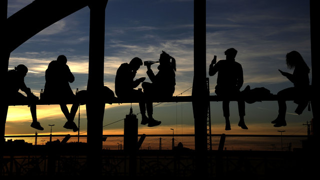 People drink wine, take pictures and enjoy the sunset at the bridge “Hackerbruecke” in Munich, Germany, Sunday, October 31, 2021. (Photo by Matthias Schrader/AP Photo)