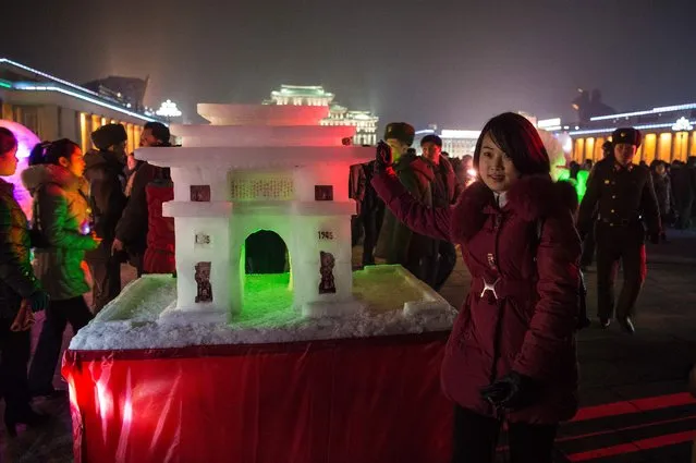 A young woman poses for a picture next to an ice sculpture at the Pyongyang Ice Sculpture Festival in Kim Il Sung Square on New Year's Eve on December 31, 2016. (Photo by Kim Won-Jin/AFP Photo)