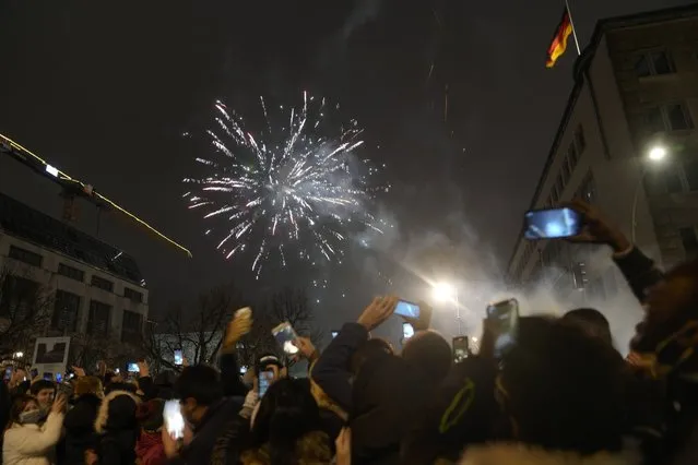 Spectators at the boulevard Unter den Linden watch fireworks as they celebrate the New Year near the Brandenburg Gate in Berlin, Germany, Saturday, January 1, 2022. Large-scale New Year celebrations are prohibited in Germany. (Photo by Markus Schreiber/AP Photo)