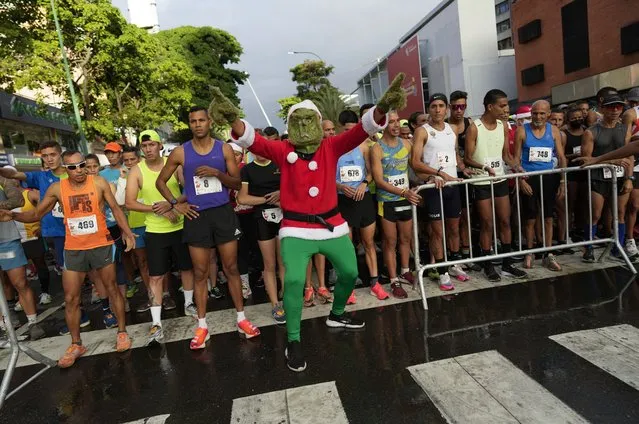 Runners wait for the start of the Santa Run 10K race in Caracas, Venezuela, Sunday, December 19, 2021. This is the first Santa Run since the start of the pandemic. (Photo by Ariana Cubillos/AP Photo)