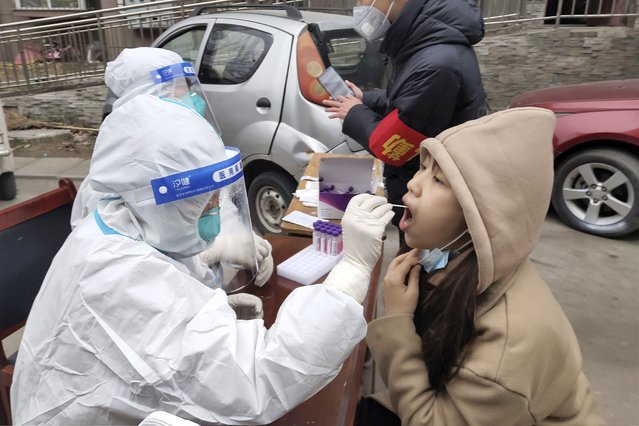 Workers collect sample from a resident during a third round of COVID-19 tests in Huaxian county in central China's Henan province Wednesday, January 12, 2022. Millions of Chinese are under lockdown in cities under the strict “dynamic zero-case policy” that has allowed China to largely contain major outbreaks, although at considerable cost to local economies. (Photo by Chinatopix via AP Photo)