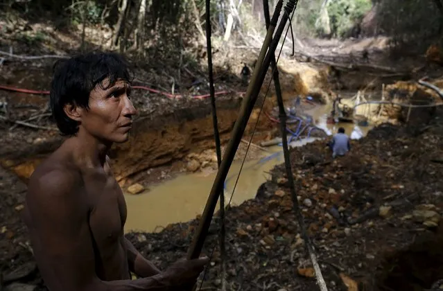 An Yanomami indian stands near an illegal gold mine during Brazil’s environmental agency operation against illegal gold mining on indigenous land, in the heart of the Amazon rainforest, in Roraima state, Brazil April 17, 2016. At over 9.5 million hectares, the Yanomami territory is twice the size of Switzerland and home to around 27,000 indians. The land has legally belonged to the Yanomami since 1992, but illegal miners continue to plague the area, sawing down trees and poisoning rivers with mercury in their lust for gold. (Photo by Bruno Kelly/Reuters)