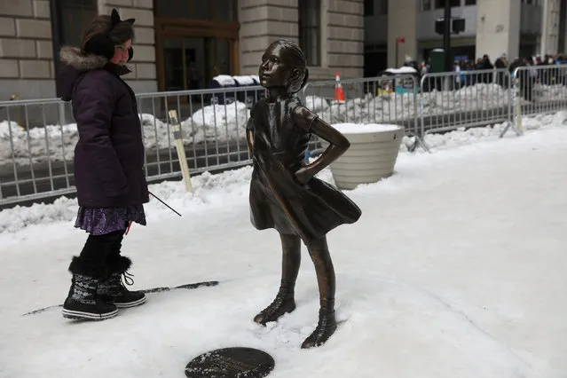 A girl looks at the 'Fearless Girl' statue which stands in front of Wall Street's Charging Bull statue in New York, U.S., March 15, 2017. (Photo by Shannon Stapleton/Reuters)