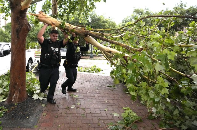 Houston Police officers move a fallen tree out of the street at Prairie and Travis Street downtown after a strong thunderstorm moved through Thursday, May 16, 2024, in Houston. (Photo by Karen Warren/Houston Chronicle via AP Photo)