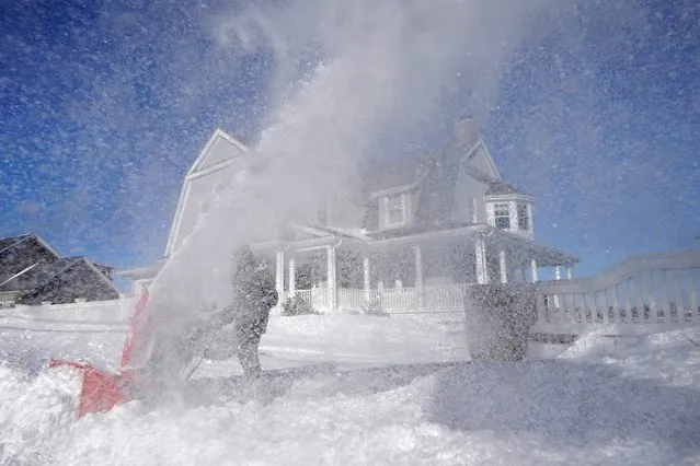 Bill McKelvey, of Scituate, Mass., uses a snow blower to clear snow in front of his home, Sunday, January 30, 2022, in Scituate. (Photo by Steven Senne/AP Photo)