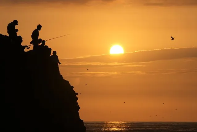 People are silhouetted while fishing during sunset at Herradura beach in Lima, Peru, Saturday, January 15, 2022. (Photo by Martin Mejia/AP Photo)