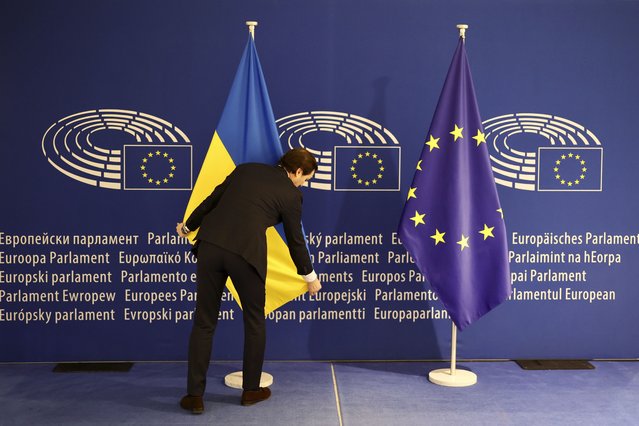 A worker stretches the Ukrainian flag before Ukraine's President Volodymyr Zelenskyy arrival at the European Parliament in Brussels, Belgium, Thursday, February 9, 2023. (Photo by Olivier Matthys/AP Photo)