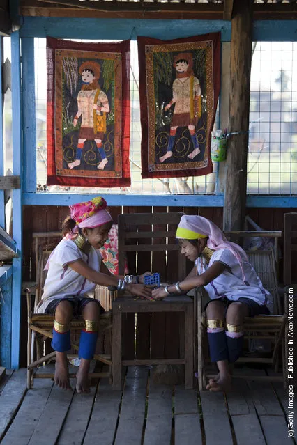 Burmese Long Neck children play as they wait for tourists to arrive at a handicraft shop on Inle Lake